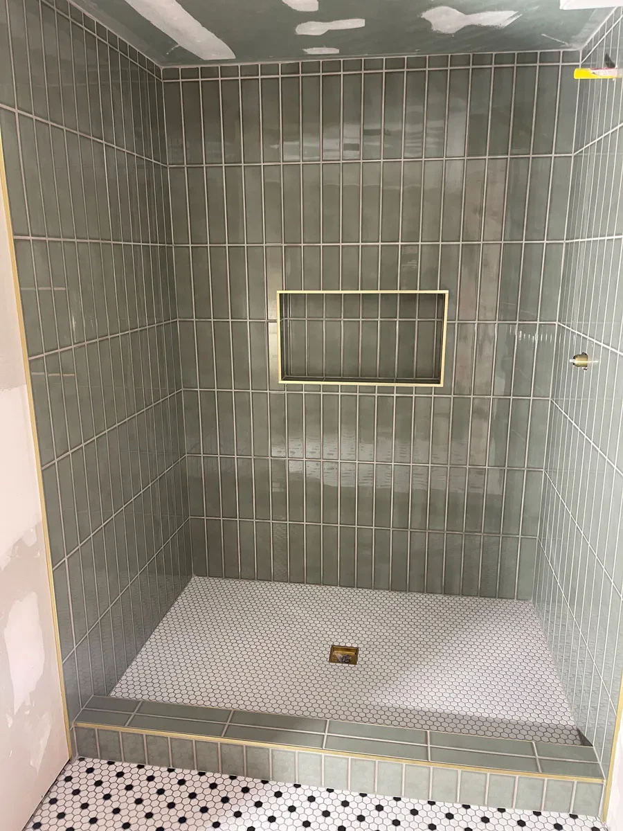Green tiled shower under construction with a niche.
